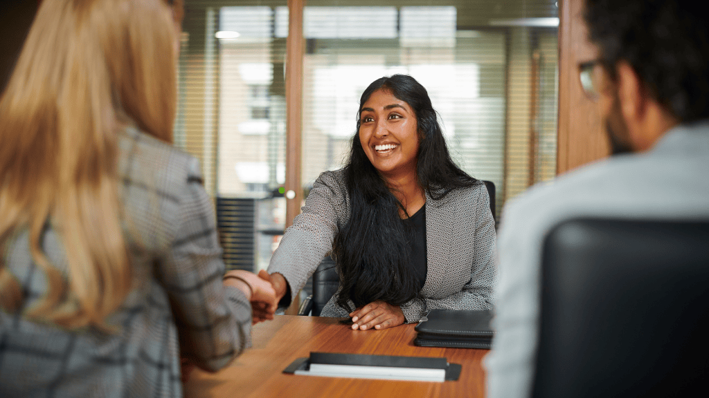 Person interviewing for a franchise related position. Female shaking hands with two people performing an interview